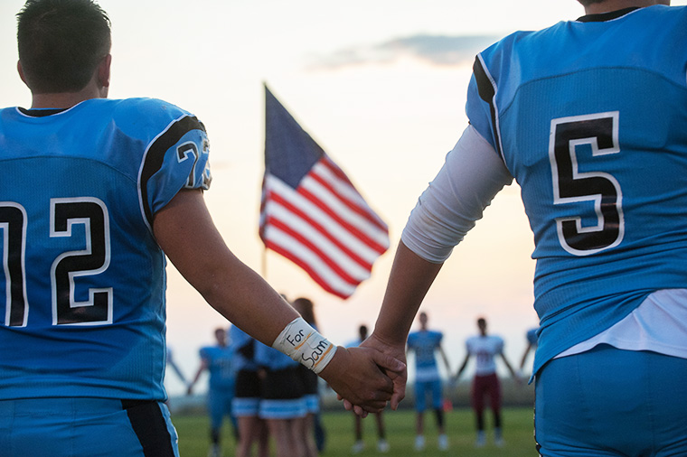 Freeman’s Dakota Steiger (72) wore an armband memorialising fellow student Sam Strahan as he joined hands with teammate Jace Phelan (5) in remembrance before the start of a football game against Medical Lake on Friday, September 18, 2017, at Freeman High School in Rockford, Washington (Photo by Tyler Tjomsland/The Spokesman-Review)