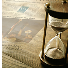 Hour glass sitting on top of a newspaper.