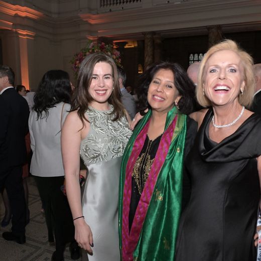 Three delegates in evening dress at a reception in a columned hall.