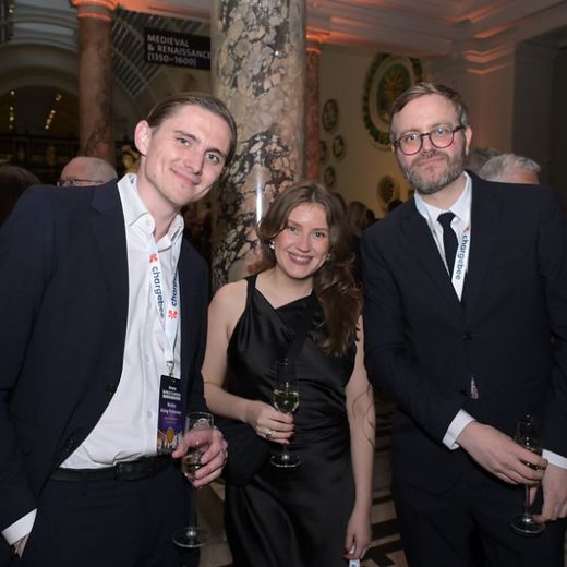 Three delegates talking between marble columns at a reception.