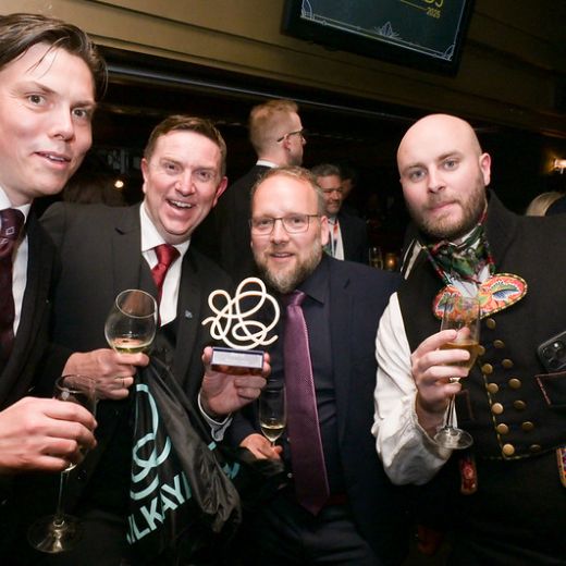 Three delegates with wine glasses, one in an embroidered waistcoat.
