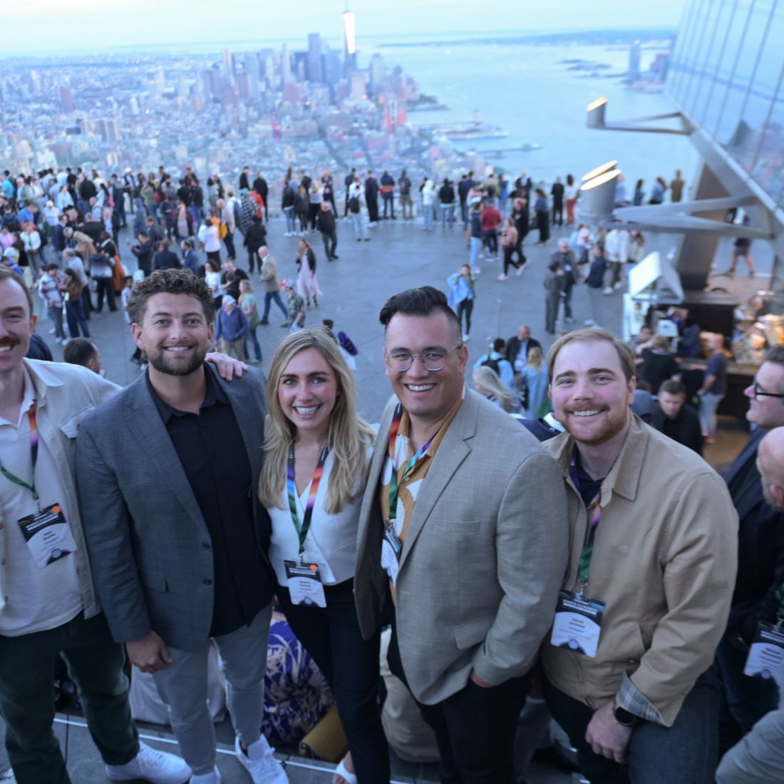 Five delegates on a terrace high above a crowded city square.