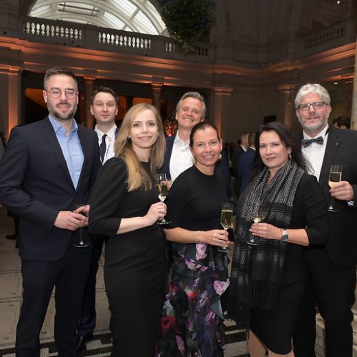 Six delegates gathered for a photo at a reception in a columned hall.