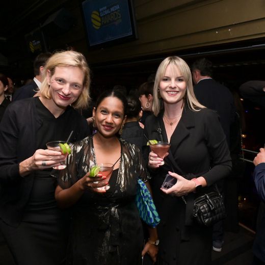 Three delegates with cocktails in a dark bar.