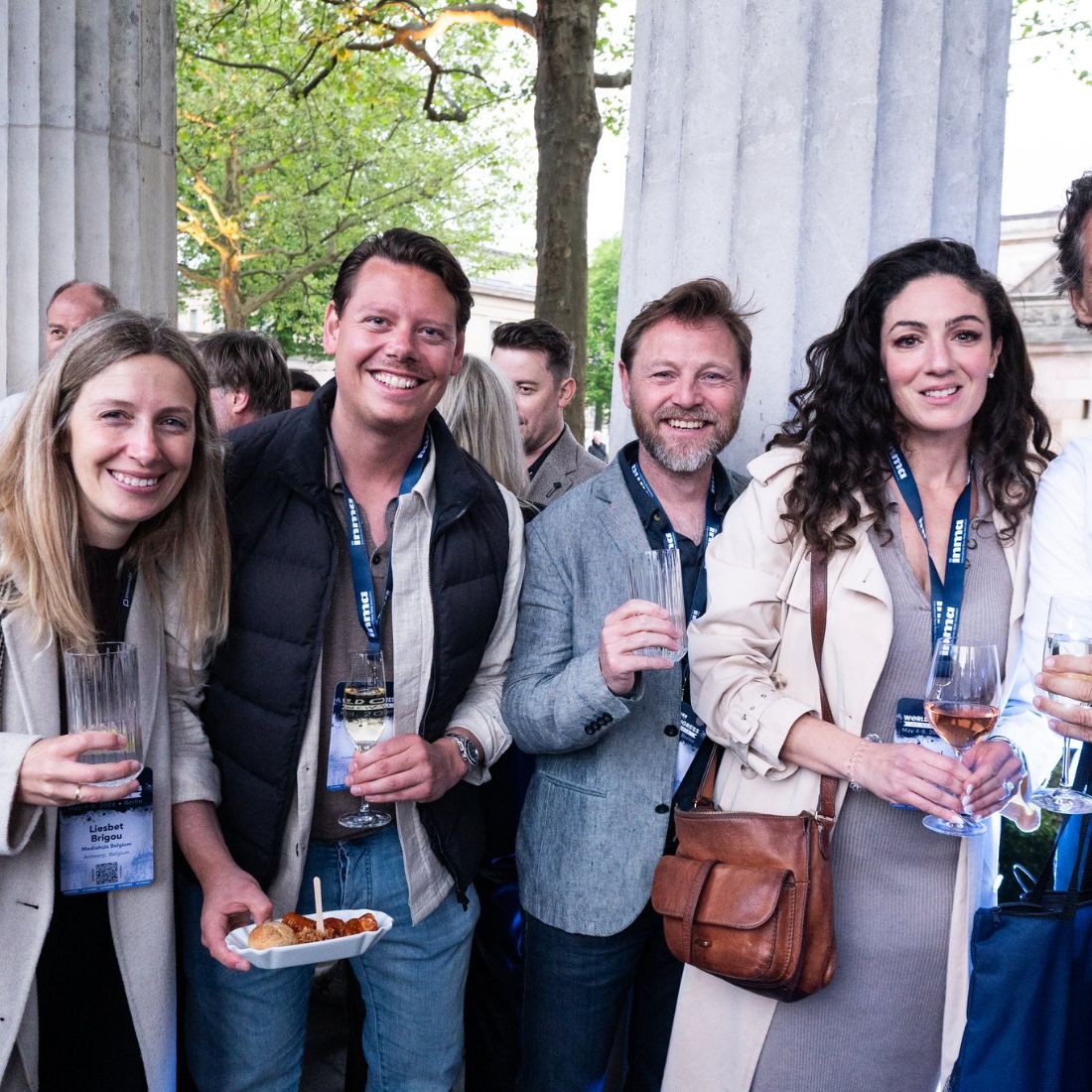 Five delegates outdoors in front of a colonnade in daylight.