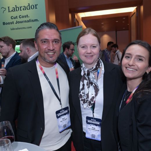 Three delegates talking in front of an exhibitor stand.