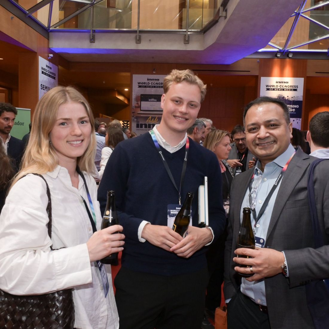 Three delegates with drinks on the conference floor.