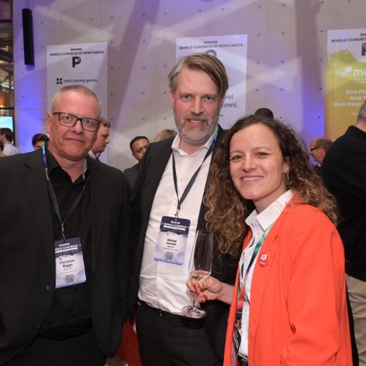 Three delegates with drinks between exhibitor stands.