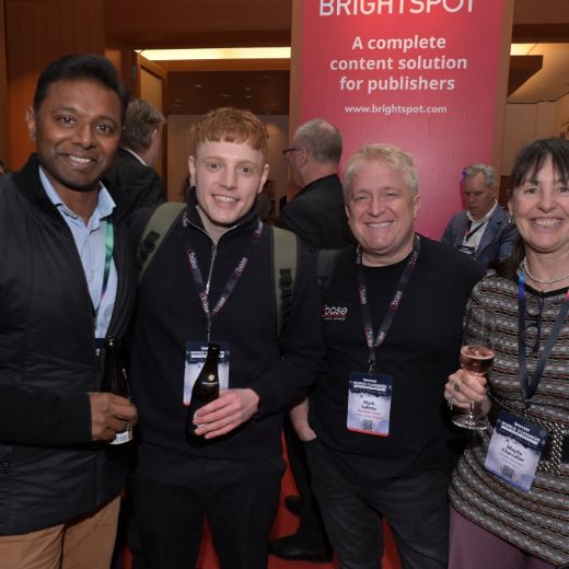Four delegates in front of an exhibitor stand.