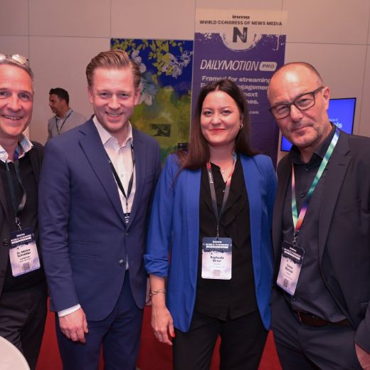 Four delegates with drinks among the exhibitor stands.