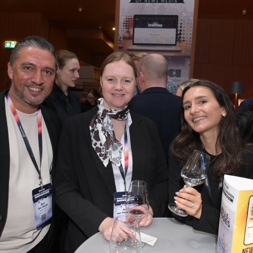 Three delegates with wine glasses at a reception.